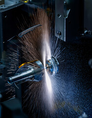 Industrial machine cutting metal with sparks flying.