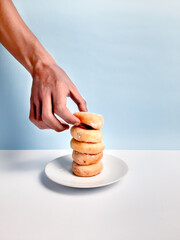Hand Holding donut with white sugar on a blue background. Close-up of Cake and sweet