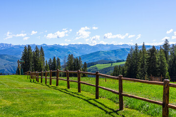 Beaver Creek village ski resort of Vail near Avon, Colorado in summer with wooden fence spruce fir trees forest and green meadow