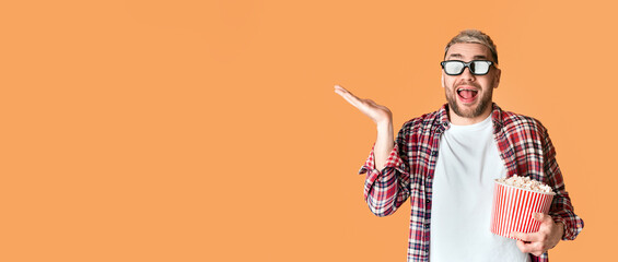 Emotional excited man with glasses and popcorn ready to watch movie, on yellow background, empty...