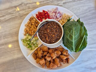 Set of Savoury leaf wraps, A royal leaf wrap appetizer with roasted peanut, dried coconut, chilly, lime, shallot and sweet dipping sauce. Famous traditional snack in Thai ancient restaurant.