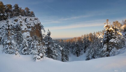 A serene winter landscape featuring snow-covered trees, a mountainous backdrop, and a clear sky at dawn.