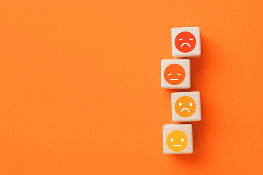 For negative thinking, mental health concept, negative mindset, support and evaluation symbol,  emoticon face on stack of wooden cube blocks on orange background