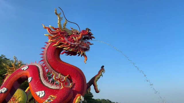 Red Chinese Dragon Statue with water fountain spraying out from the dragons mouths in Nakhon Sawan Park