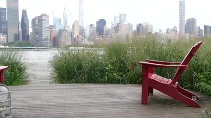 New York City waterfront skyline, Manhattan Midtown buildings, riverfront skyscrapers by East river water. Waterside cityscape view, Gantry Plaza Park, Long Island, Queens. United States. Chair bench.