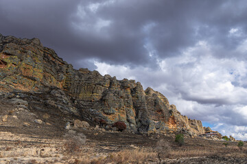 Majestic sandstone cliffs and layered rock formations create dramatic natural scenery against a stormy sky. These geological formations were formed during the Jurassic period. Madagascar.