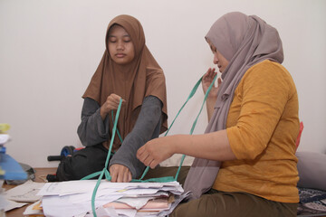 Two Asian muslim female, mother and daughter cleaning room together, clearing out unused items , decluttering