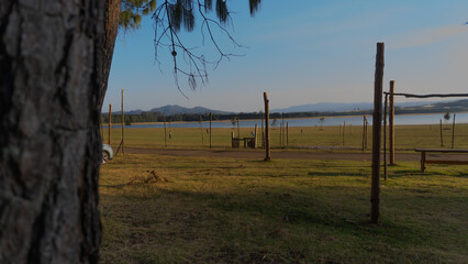 Open field with wooden poles near a lake under blue sky