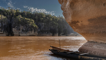 Canoes hollowed out of wood are moored at the entrance to the cave. The rock overhangs the...