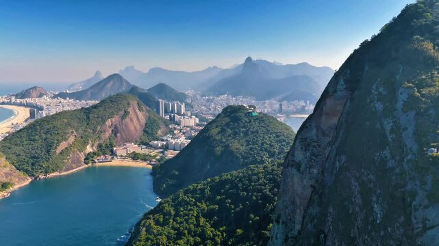 Drone ascends Sugarloaf alongside Bondinho cable car, revealing Rio&rsquo;s coastline and lush mountains below