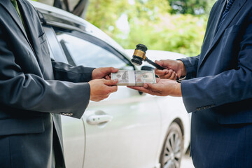 Asian clients engage with a car insurance agent beside a wrecked vehicle. They examine the policy...