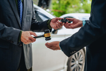 An Asian businessman buys a car, signs a contract with the salesman, and receives the keys. They discuss essential terms, covering car leasing, finance, and loan laws to finalize the purchase