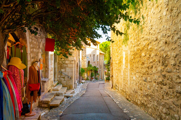 Obraz premium A narrow shady cobblestone alley with shops and boutiques in the hilltop medieval village of Saint-Paul de Vence, France, in the Provence region of Southern France.