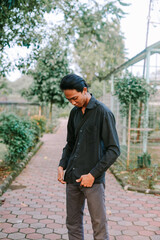 A young man in a black shirt stands outdoors