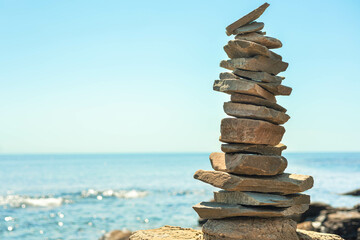 Stone tower at sunny sea coast beach balance harmony zen symbol. Natural pebble pyramid