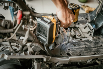 Mechanic use electric screwdriver or impact driver to repair motorcycle in garage, Maintenance and repair motorcycle concept