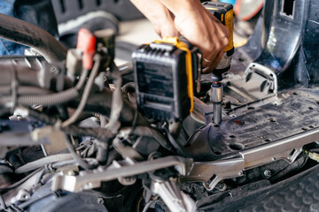 Fototapeta premium Mechanic use electric screwdriver or impact driver to repair motorcycle in garage, Maintenance and repair motorcycle concept