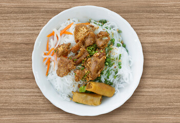 A bowl of Vermicelli Noodles with Grilled Pork and Egg Rolls, Vietnamese grilled pork and rice noodles. Bun thit nuong. Fried Spring Rolls Cold Rice Vermicelli with sauce served in bowl isolated. 