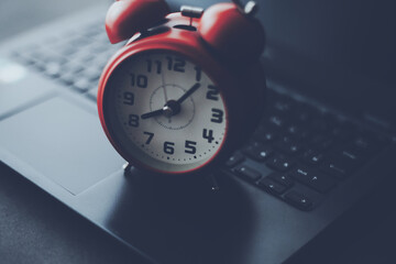 目覚まし時計と開いたノートパソコン
