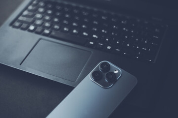 スマホのトリプルカメラと開いたノートパソコン