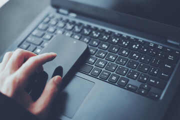 スマホの操作と開いたノートパソコン