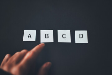 黒背景に置かれたABCDと人の手元