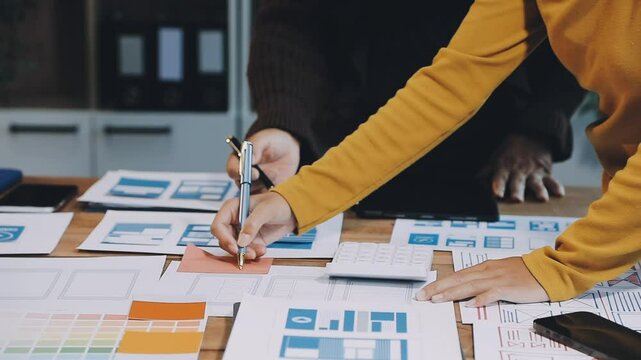 Web design process. The web designer creating a mockup of the mobile application according to the customer's brief. Samples and sketches laying at the table