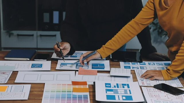 Web design process. The web designer creating a mockup of the mobile application according to the customer's brief. Samples and sketches laying at the table