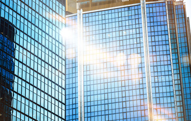 A view of several modern skyscrapers with glass facades, illuminated by the sun's rays.