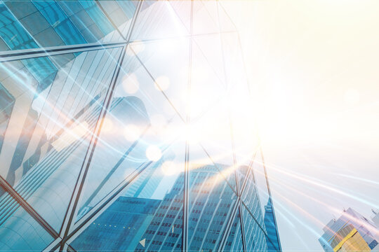 A low angle view of a glass skyscraper with sunlight reflecting off the windows. The building is modern and sleek, with a sharp and angular design.