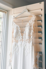 Close-up of a wedding dress with a lace top hanging on a hanger in the bride's room. A wedding...