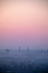 Fototapeta premium The Beautiful Wind Turbines Gracefully Silhouetted Against a Serene and Misty Sunset Sky