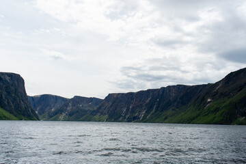 Obraz premium A picture taken aboard the ferry on Western Brook Pond, offering stunning views of the surrounding fjord and natural beauty of Gros Morne National Park, perfect for a peaceful and scenic boat ride.