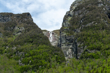 A stunning waterfall cascades from the top of a cliff face in Gros Morne, adding to the dramatic beauty and natural allure of this rugged and serene national park.