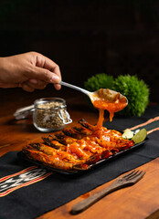 hand pouring oyster sauce onto grilled prawns served with garnish