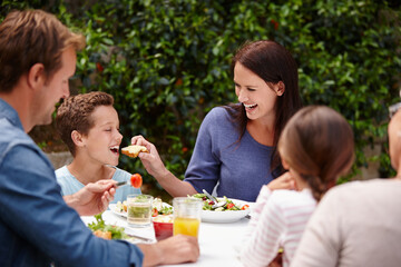 Happy family, eating and child with bread for thanksgiving dinner, food or nutrition at table together. Mother, kid or boy with smile for bite, snack or meal for bonding, dining or holiday feast