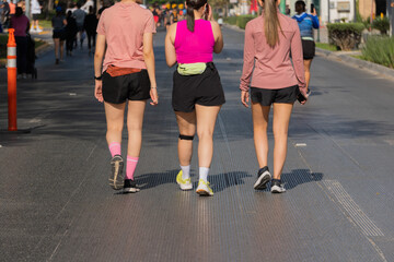 Three unrecognizable young Latina women walking on city street in sportswear