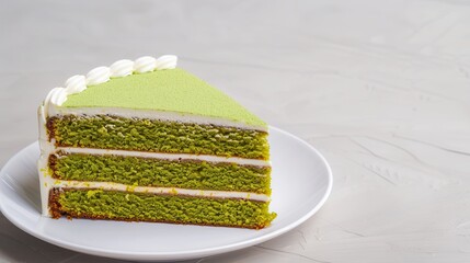 Organic matcha dessert. A vibrant slice of green cake with layers and cream frosting, beautifully presented on a white plate against a minimalistic background.