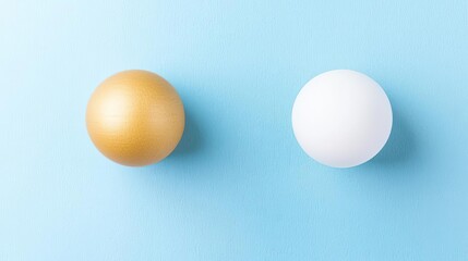 Two spherical objects, one gold and one white, on a light blue background.