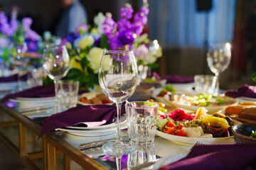 Beautiful festive table setting with flowers and purple napkins. 