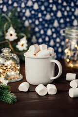 Christmas drink hot chocolate with marshmallows at festive illuminated decoration. Selective focus