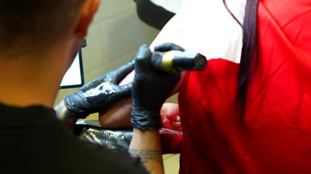 Tattoo artist checking the tattoo of a dog, applies vaseline and continues drawing with black ink