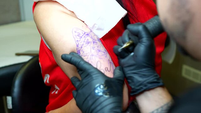Tattoo artist applying some vaseline on the tracing before tattooing husky on upper arm