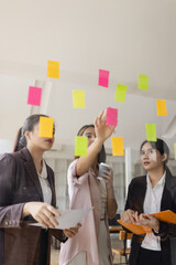 Asian businesswoman teamwork planning with sticky notes and new ideas on a glass wall, Business...