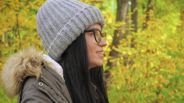 Traveling in nature. A young beautiful girl, in an autumn forest, enjoys the beauty of autumn nature, photographs objects she likes, smiles. Slow motion.