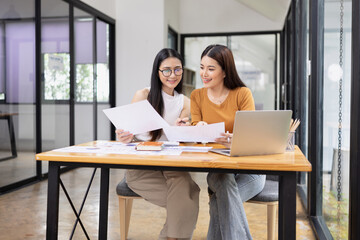 Fototapeta premium young asian businesswoman working on laptop with finances analysis report at desk in office, business financing, accounting banking,