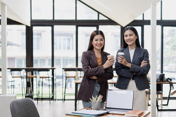 Two Asian business female talking together with partner standing in office. 