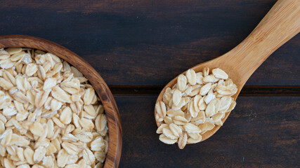 Wooden bowl and spoon with oats on rustic wooden background, ideal for healthy food concepts.