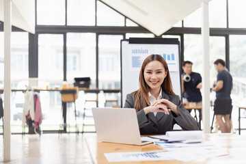 young asian businesswoman working on laptop with finances analysis report at desk in office, business financing, accounting banking,