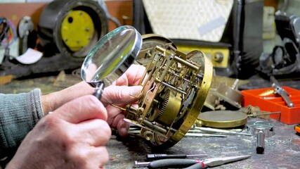 Vintage clockwork. The hands of an old master carefully adjust an antique clockwork, bringing it back to life. Restoration of antiques.